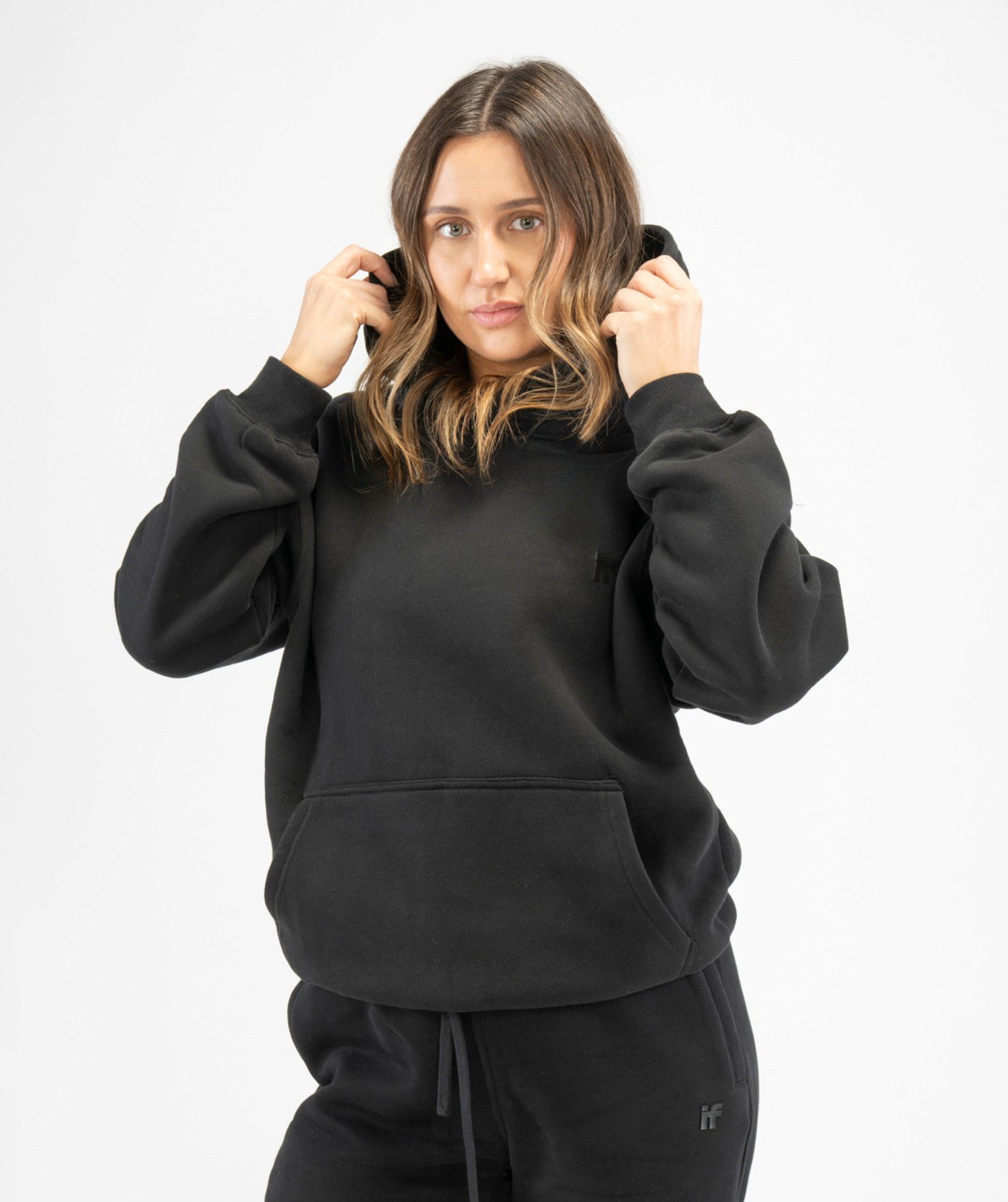 Front view of women’s black pullover gym hoodie showing relaxed fit and minimalist design
