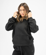 Front view of women’s black pullover gym hoodie showing relaxed fit and minimalist design