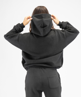 Rear view of women’s black oversized hoodie showing oversized hood and smooth back panel