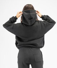 Rear view of women’s black oversized hoodie showing oversized hood and smooth back panel