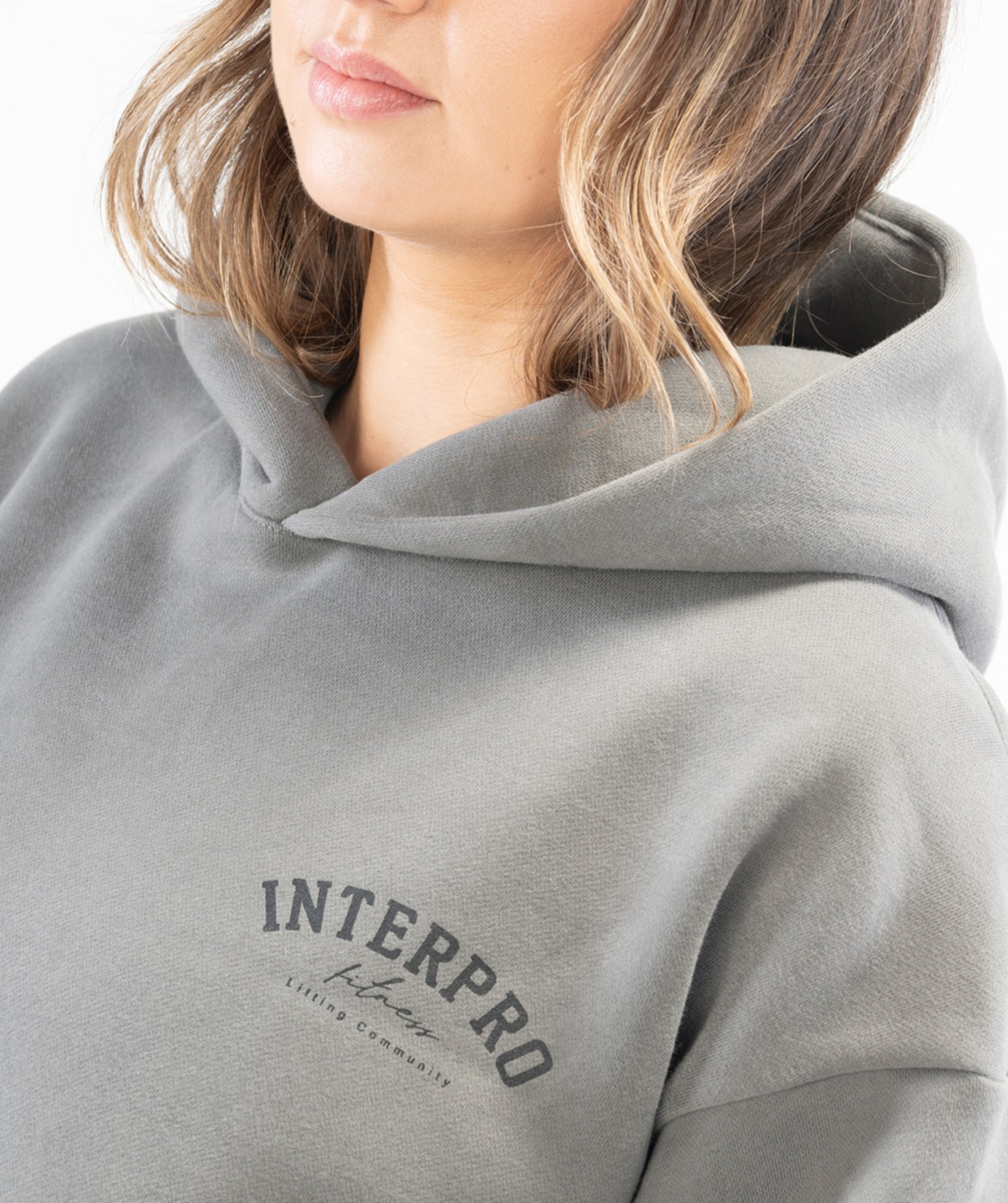 Close-up of Interpro Fitness logo on grey oversized hoodie showing printed black logo