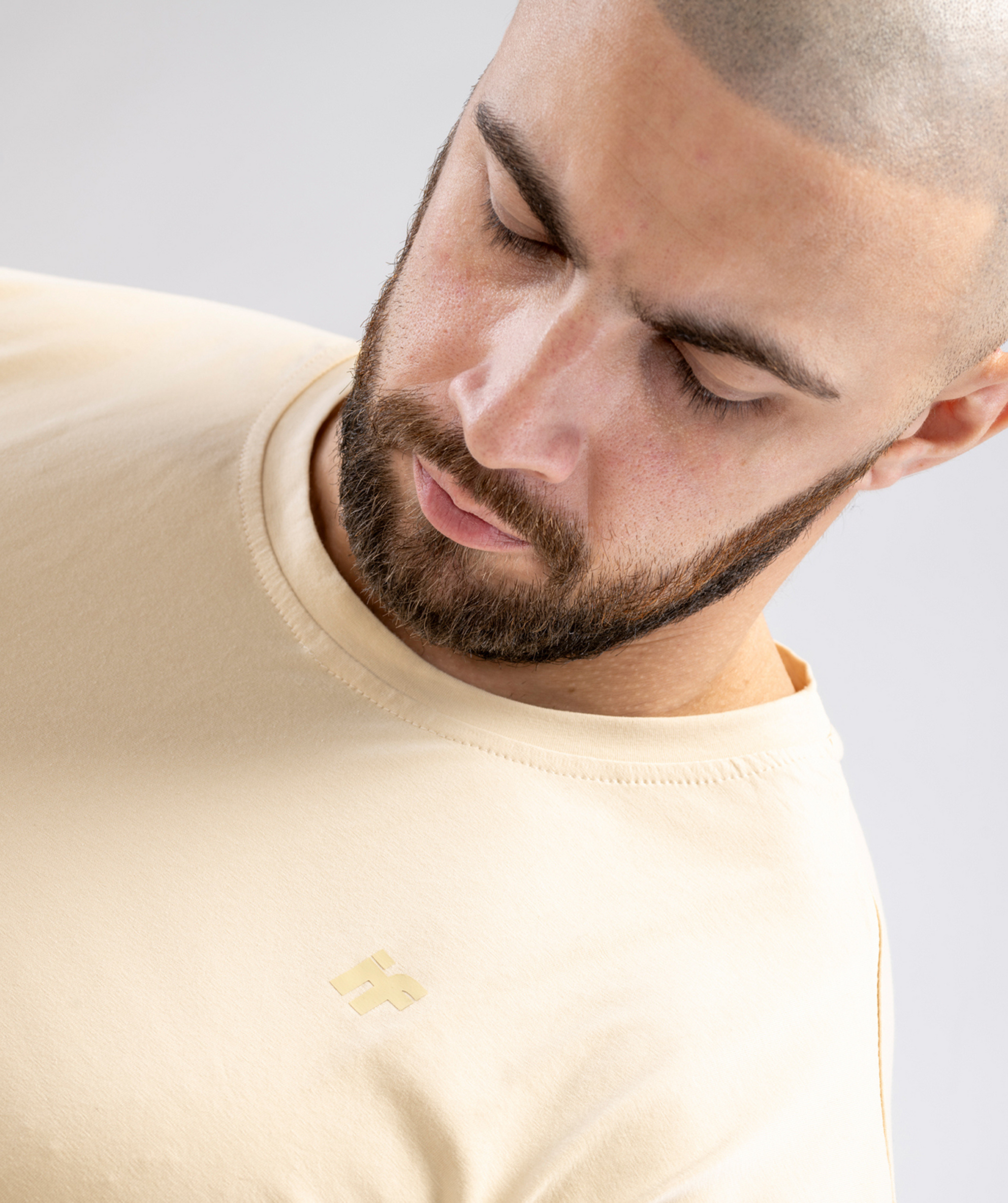 Fabric texture detail of beige men’s gym T-shirt showing logo.