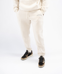Front view: Interpro Fitness Men’s Crème Joggers, front view showing tapered fit and stylish pose with hands in pockets.