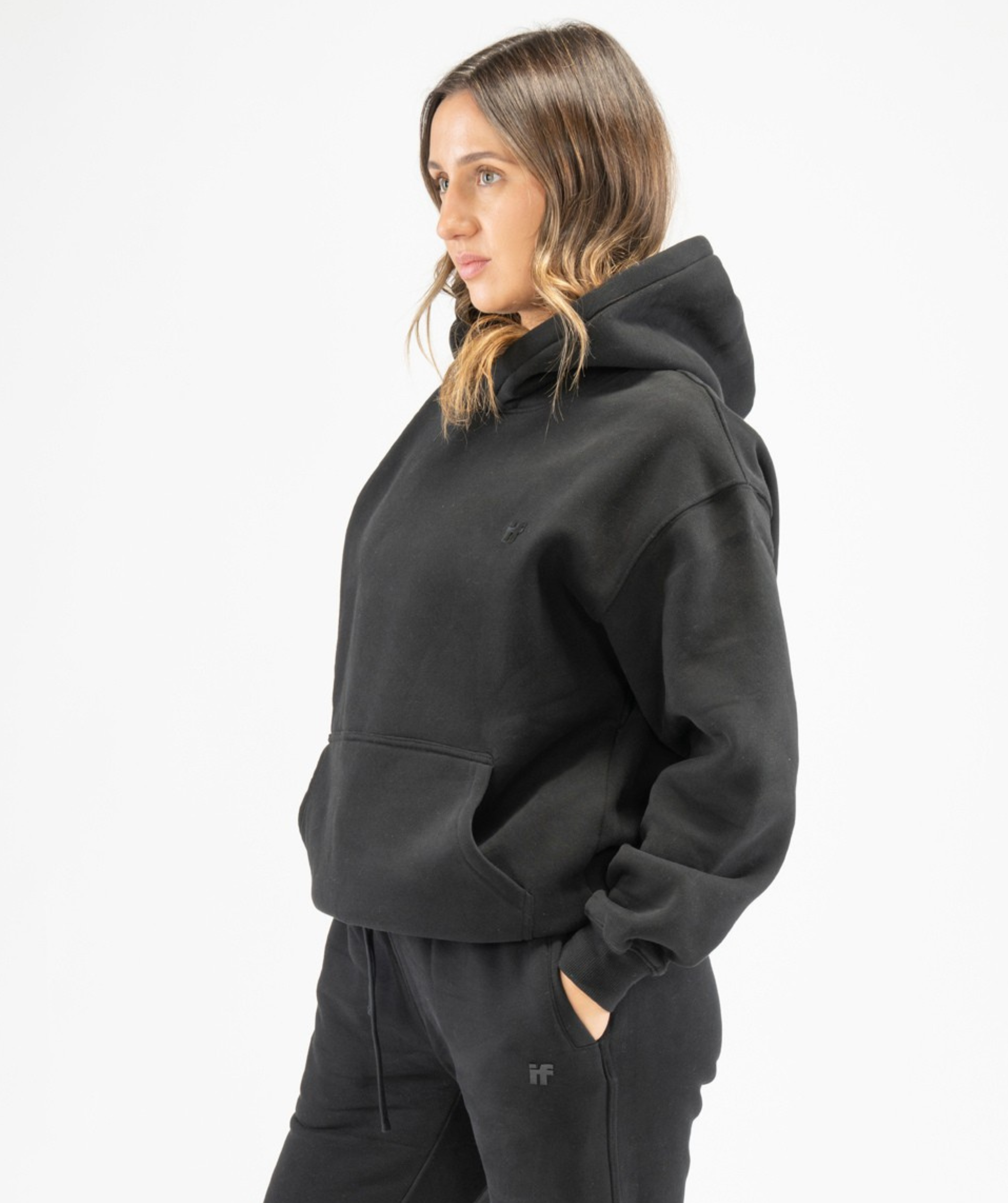 Side angle of women’s black pullover gym hoodie showing dropped shoulders and loose fit