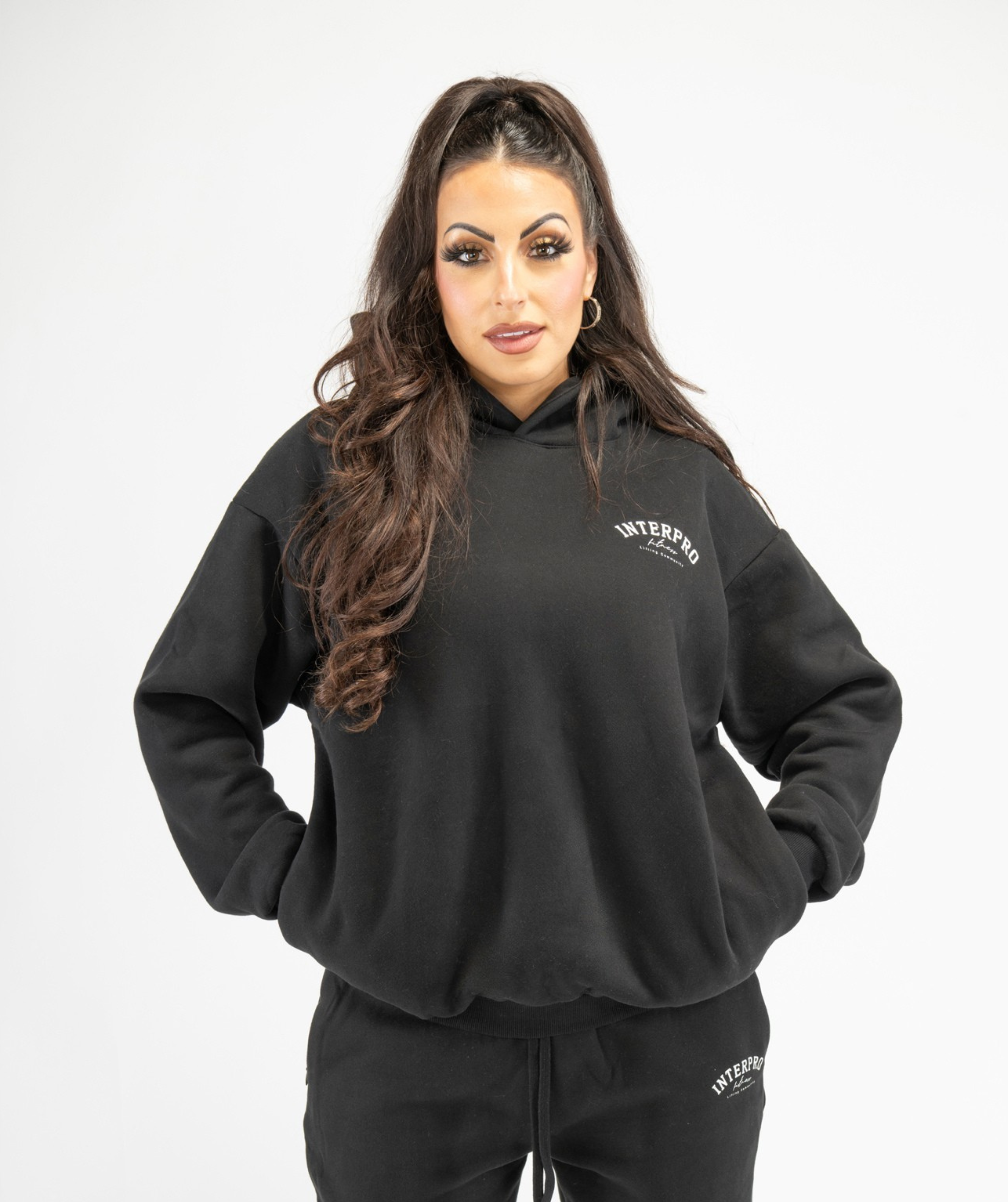 Front view of women’s black oversized pullover hoodie showing relaxed fit and dropped-shoulder design