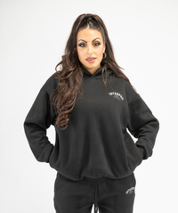 Front view of women’s black oversized pullover hoodie showing relaxed fit and dropped-shoulder design