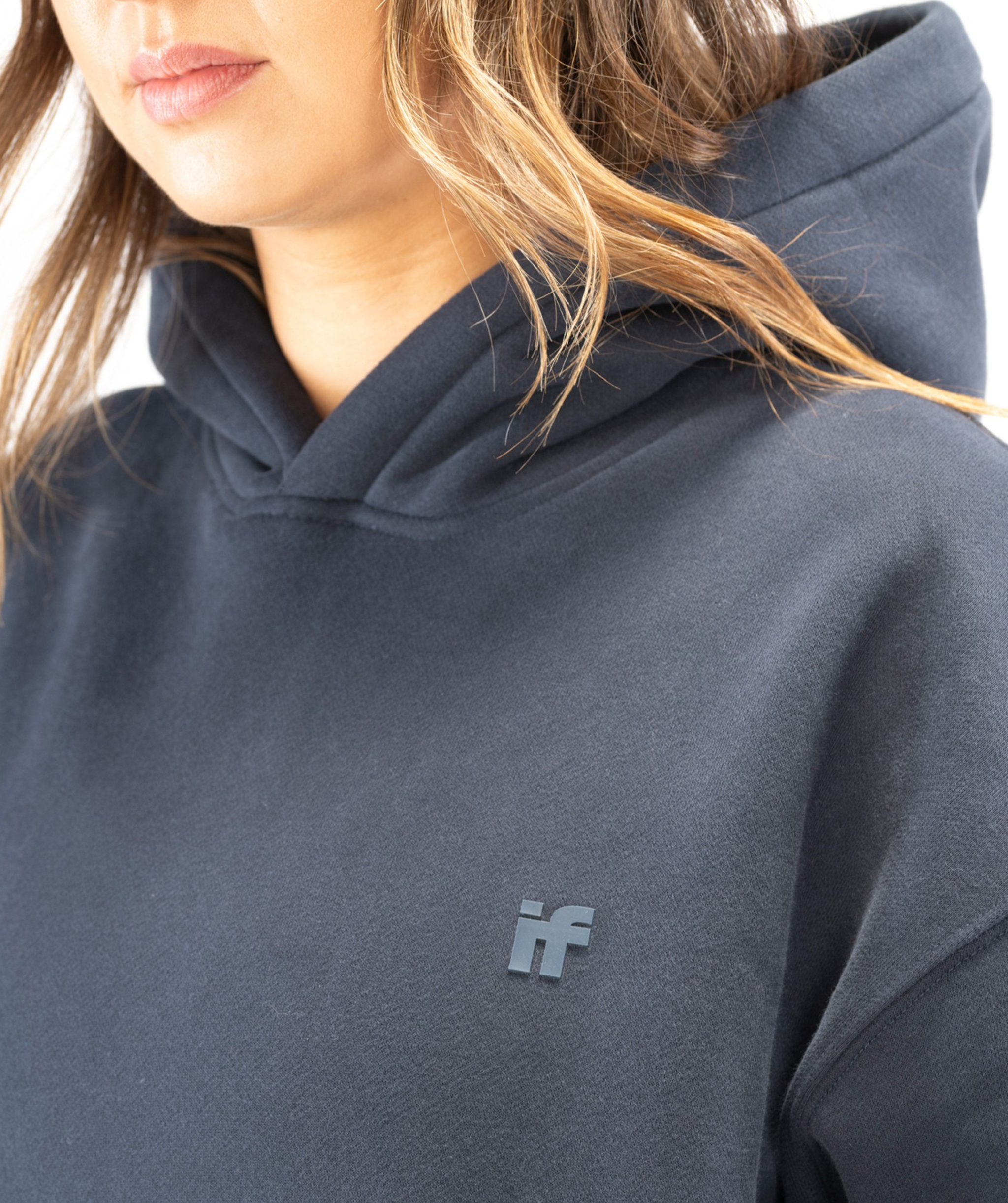 Close-up of Interpro Fitness IF silicone logo on women’s navy blue hoodie showing raised detailing