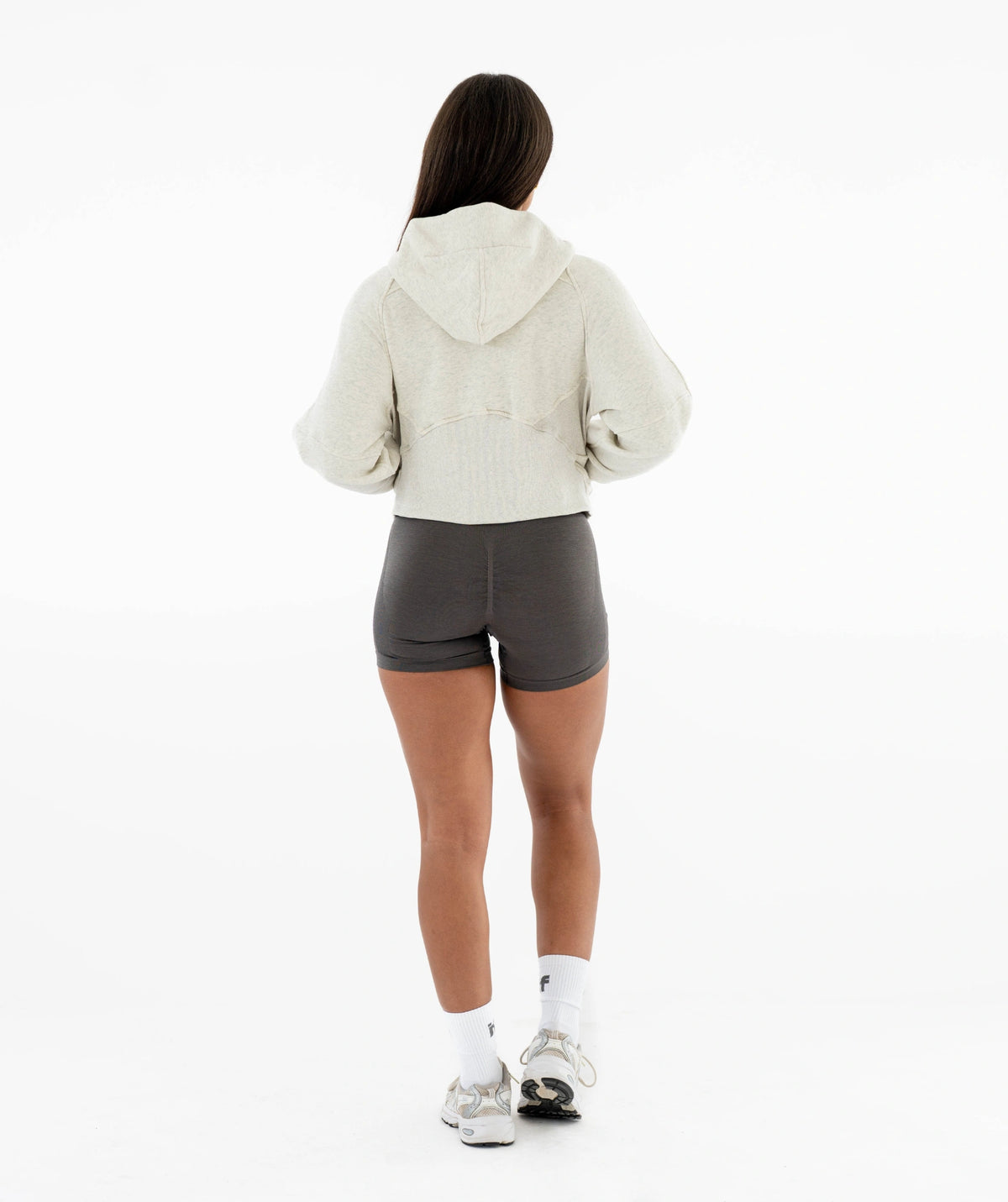 Person wearing a beige hoodie and gray shorts