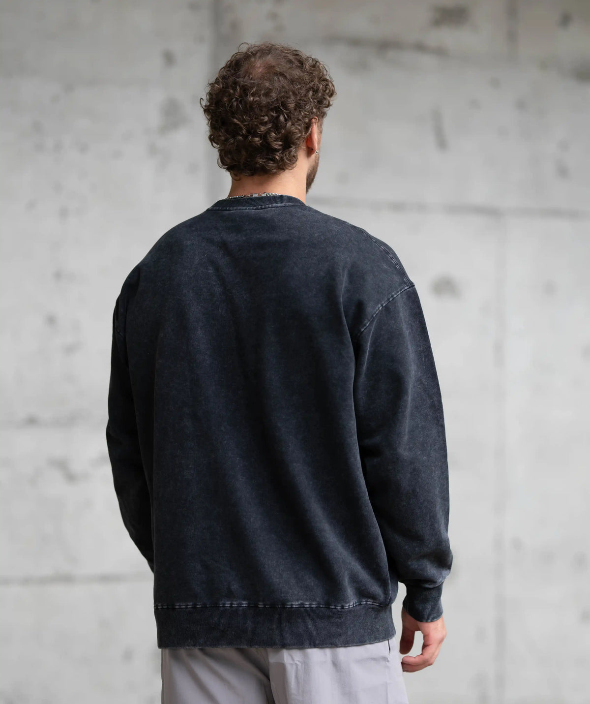  black sweatshirt against a gray concrete wall