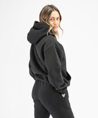Back angle of black women’s workout hoodie highlighting relaxed shape and smooth finish
