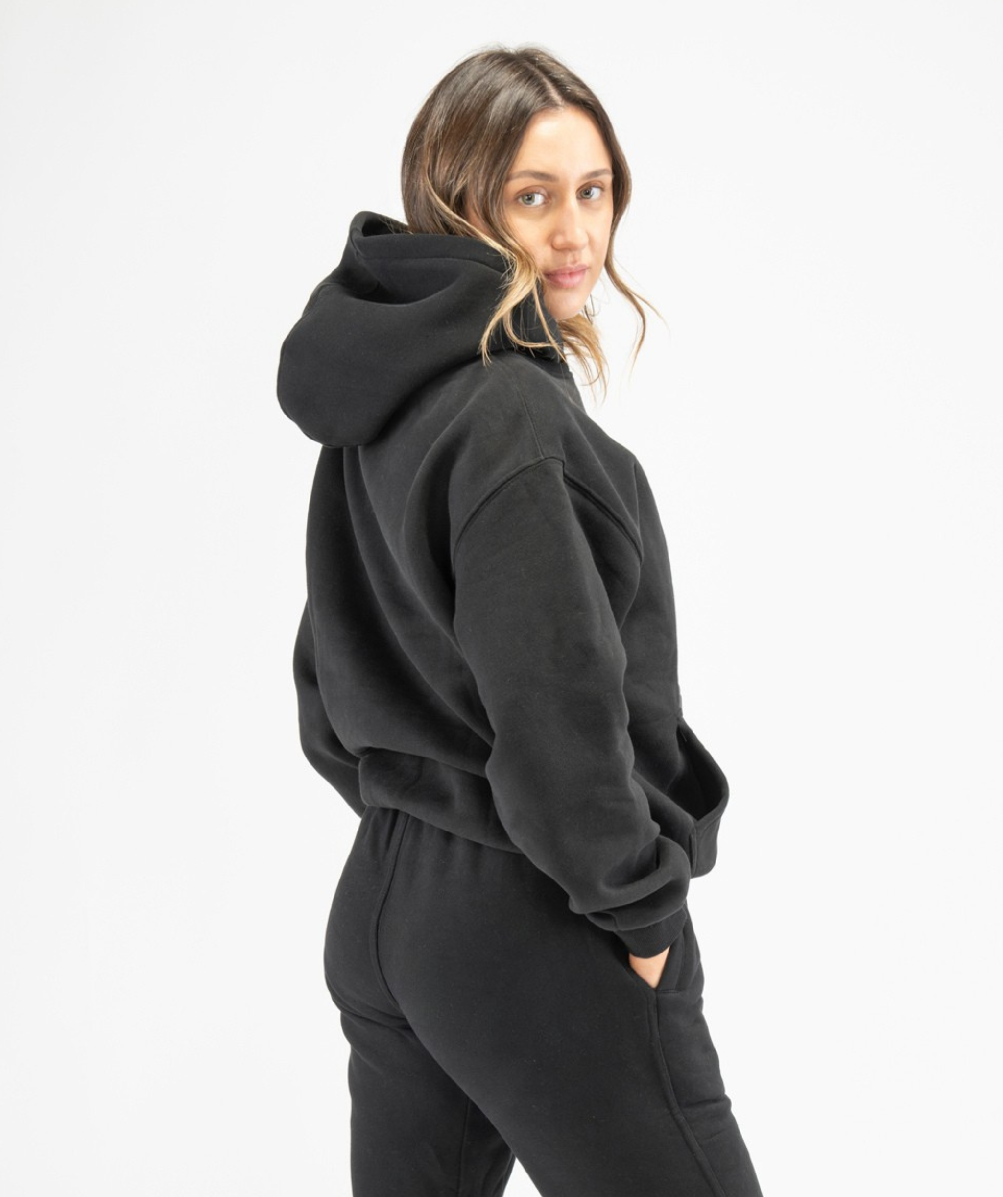 Back angle of black women’s workout hoodie highlighting relaxed shape and smooth finish