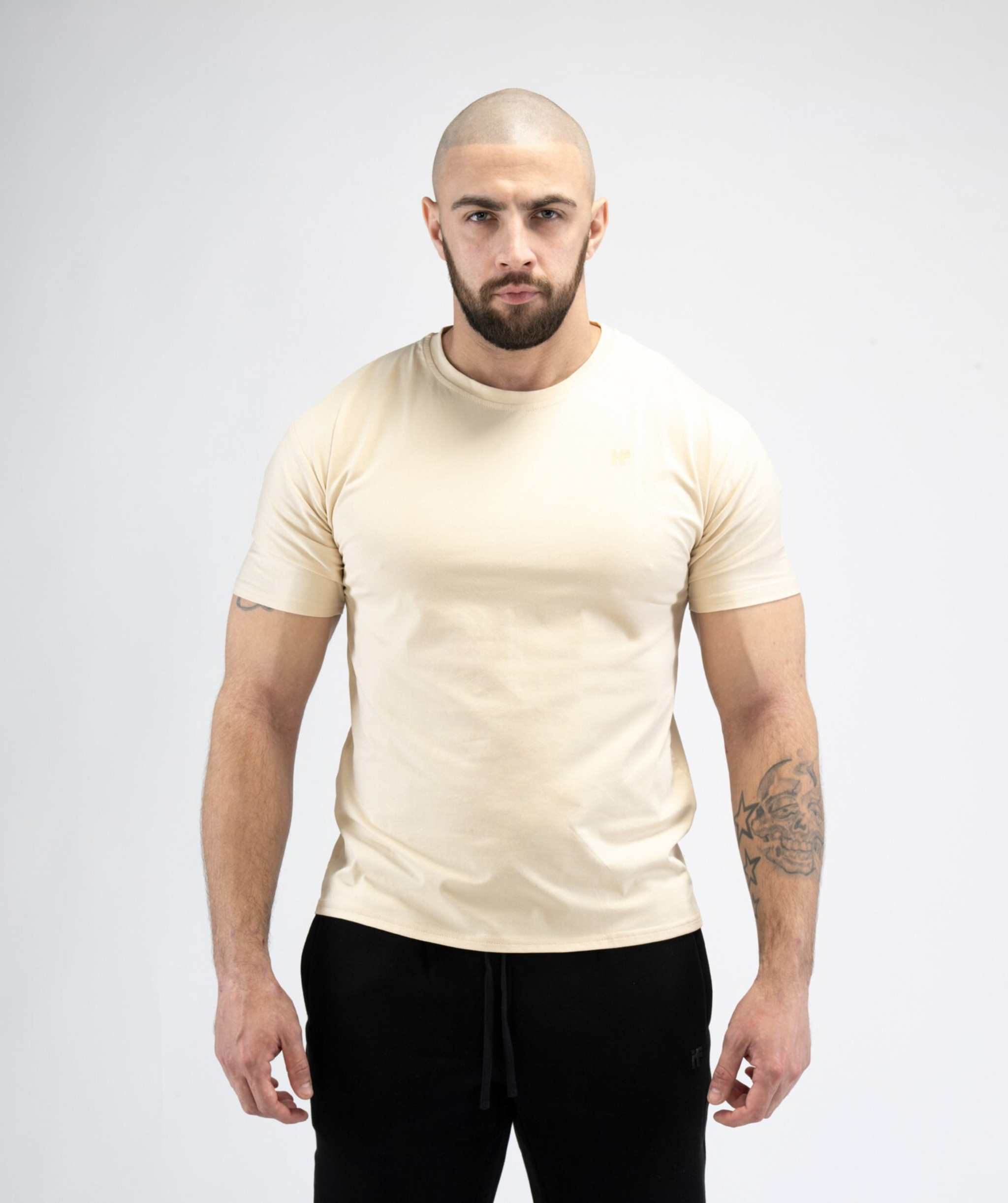 Male model wearing Interpro Fitness Men’s Beige Gym Tee with fitted athletic shape.