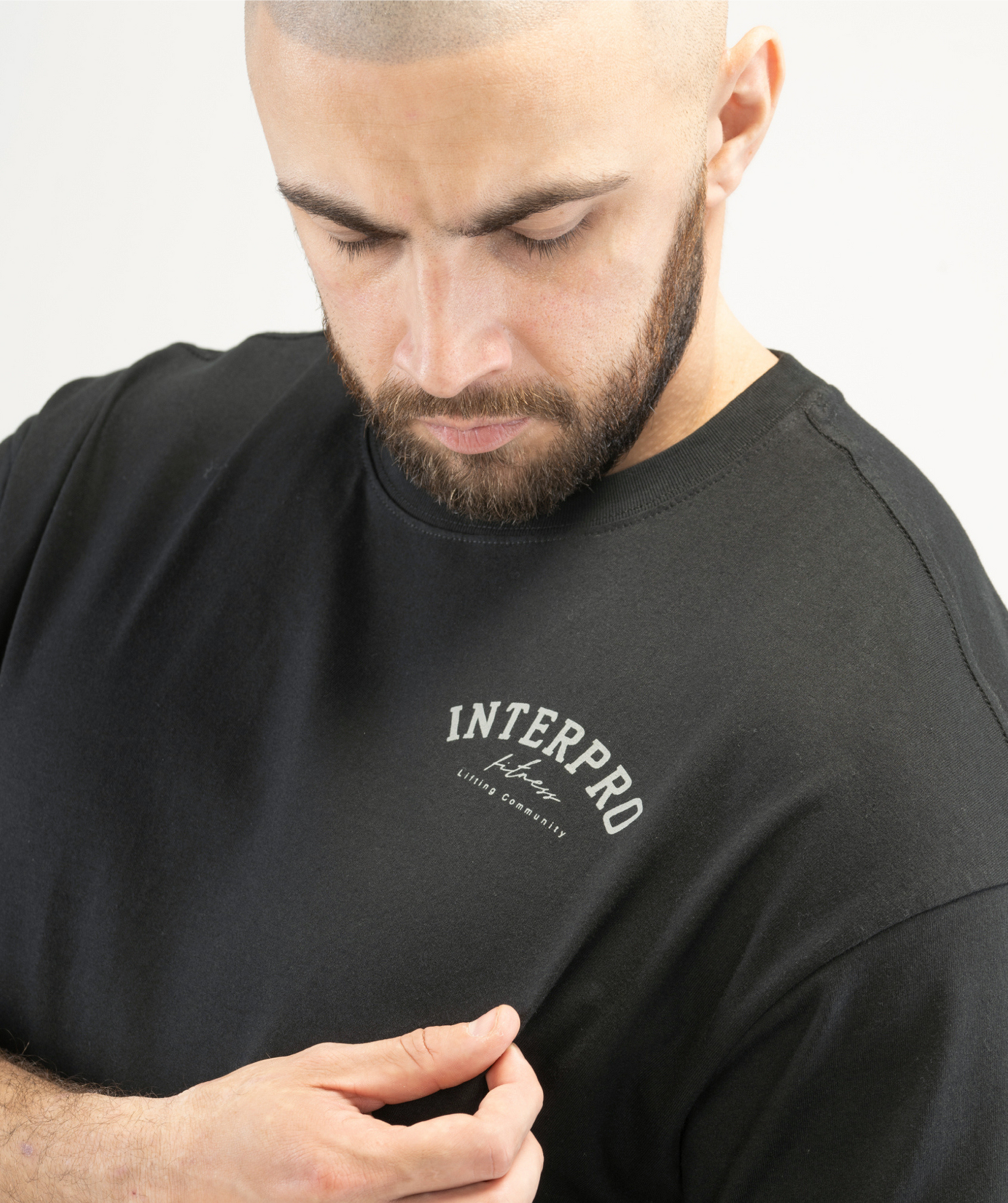 Detailed shot of the grey Interpro logo on the Men’s Black Oversized Tee.