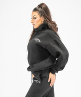 Side-profile shot of black oversized pullover hoodie highlighting longline shape and relaxed feel