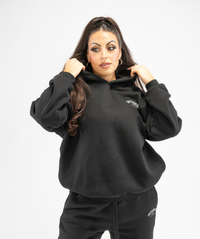 Front-facing shot of black oversized women’s hoodie highlighting loose silhouette and casual streetwear style