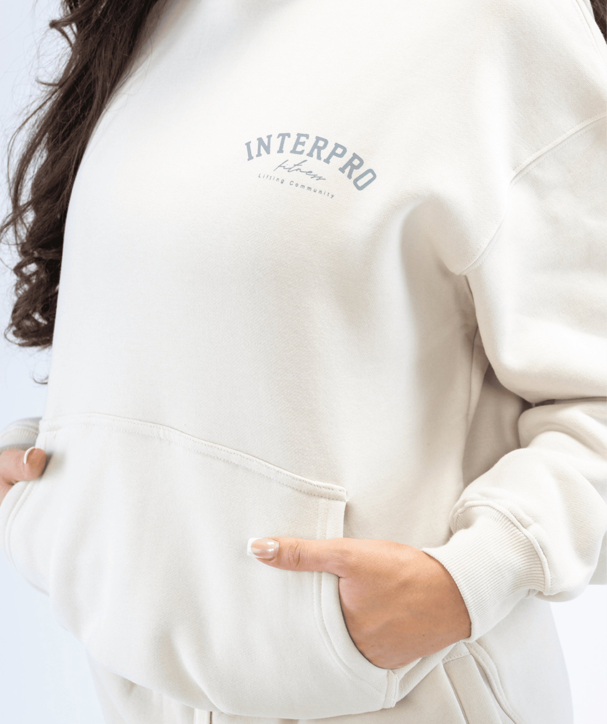 Close-up of fabric texture on creme pullover hoodie featuring premium cotton-blend material and close up of logo