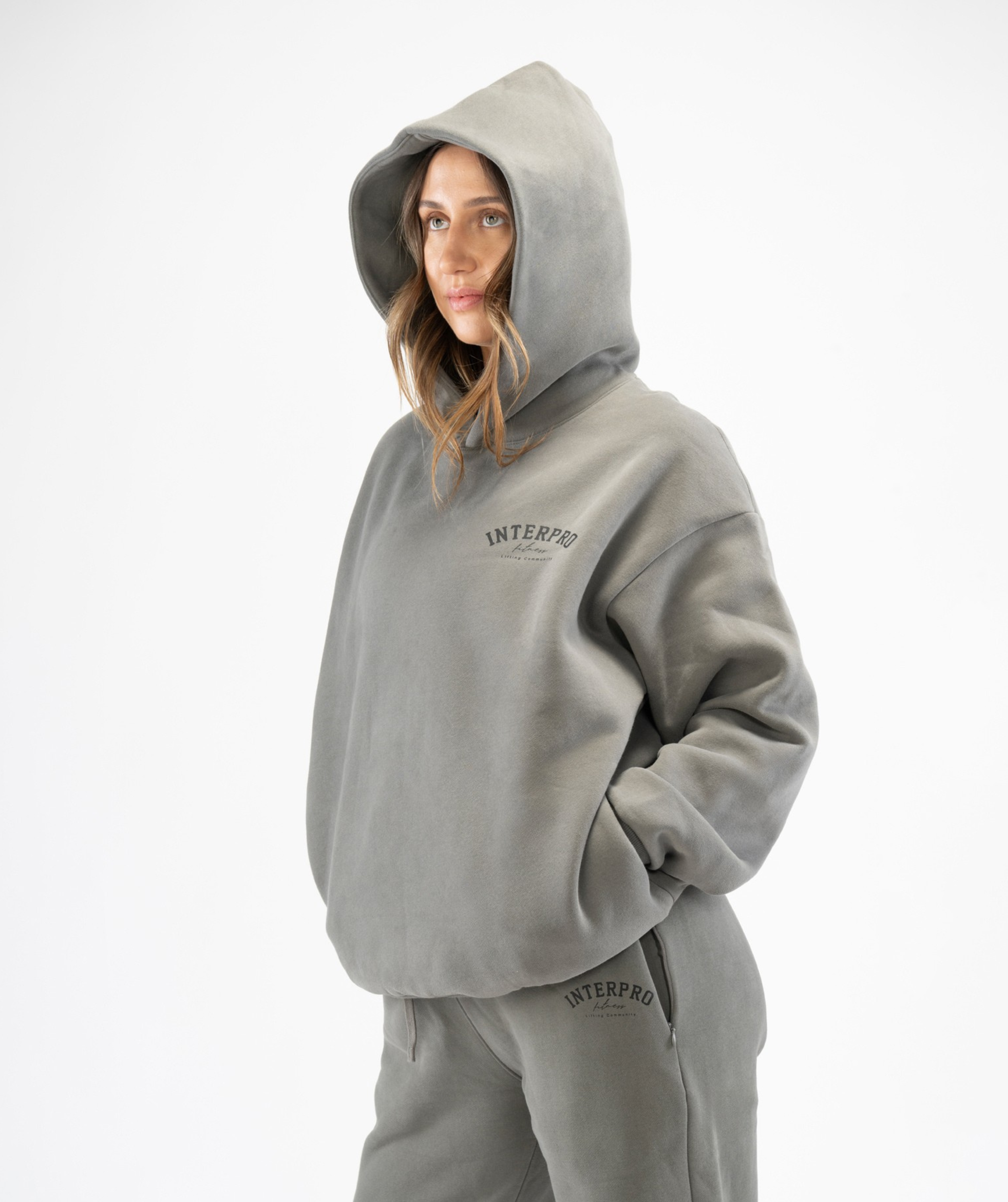 Women’s grey oversized hoodie front/side angle displaying boxy shape and comfortable drape with hood up