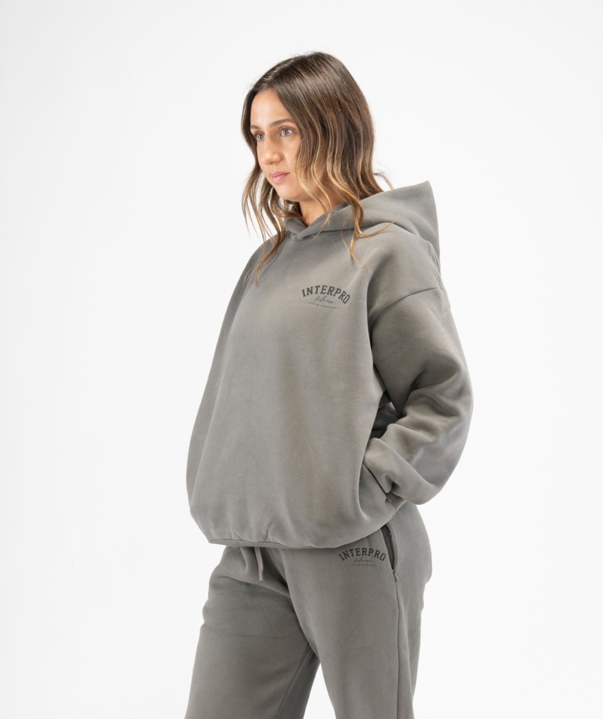 Side angle of women’s grey oversized Interpro Fitness hoodie showing dropped shoulders and roomy fit