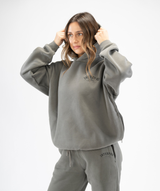 Side-profile of grey oversized women’s hoodie highlighting relaxed drape and casual athleisure style hood half up