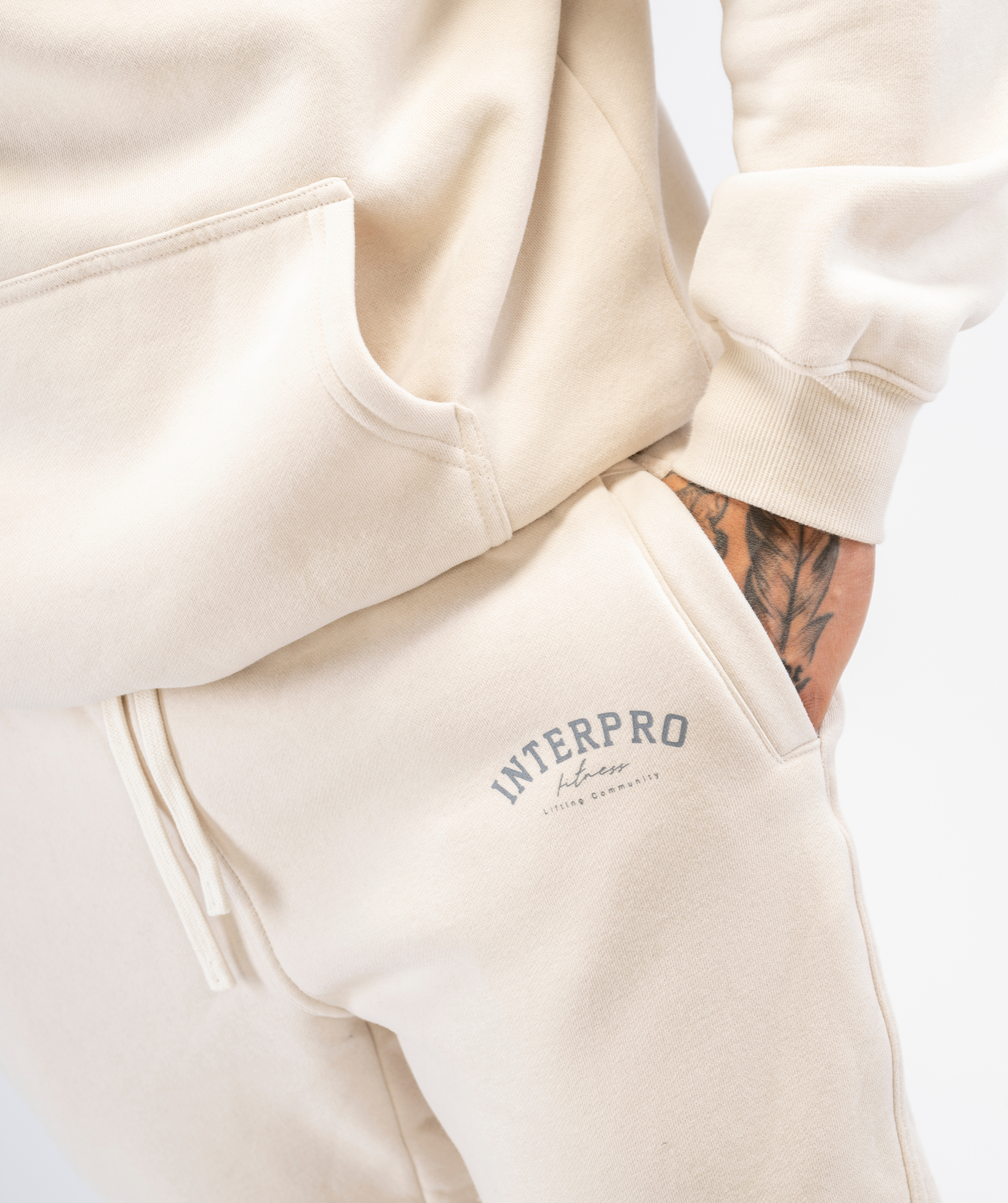 Close-up of mens creme joggers fabric and stitching, pocket and logo from Interpro Fitness.